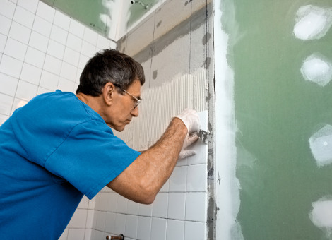 Worker installing tiling in bathroom renovation